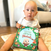 Un bambino sorride e legge dal suo libro personalizzato sui desideri di Natale.