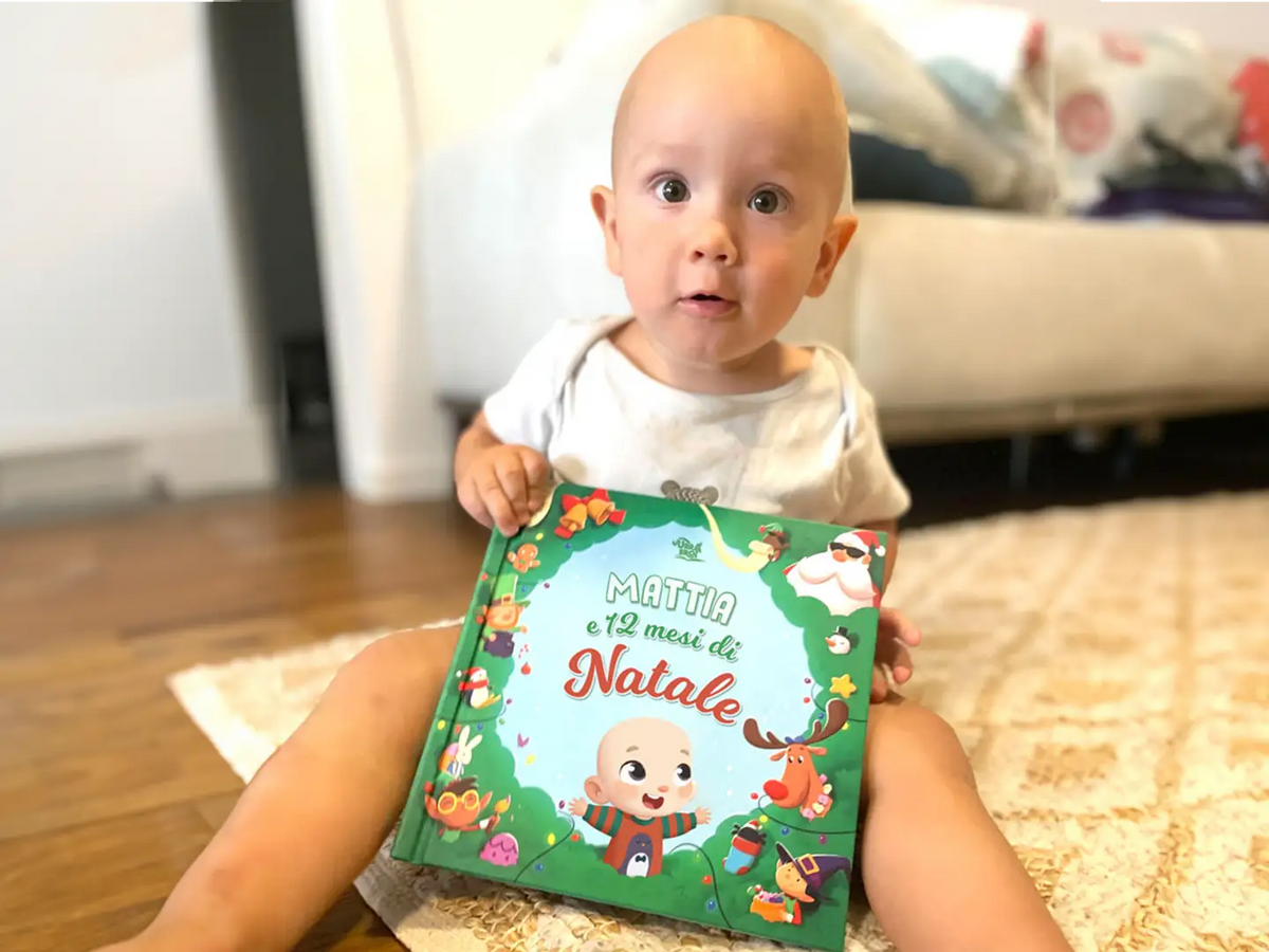 Un bambino sorride e legge dal suo libro personalizzato sui desideri di Natale.