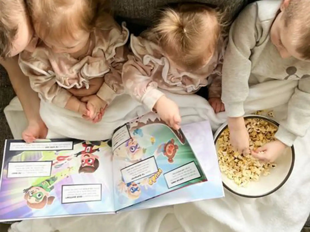 4 bambini seduti sul divano, mangiano popcorn e sfogliano il miglior regalo per i compleanni
