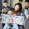 Una madre seduta sul divano con i suoi 3 figli che sfogliano il loro libro personalizzato per famiglie.