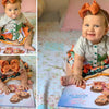 Una bambina felice sta leggendo un libro personalizzato che la rappresenta insieme ai suoi due fratelli e alla mamma.