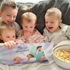  Bambini che sorridono mentre leggono il loro libro personalizzato di Urrà Eroi