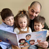 Papà tiene i suoi tre bambini tra le braccia e sta leggendo un libro personalizzato che include storie divertenti su di loro.