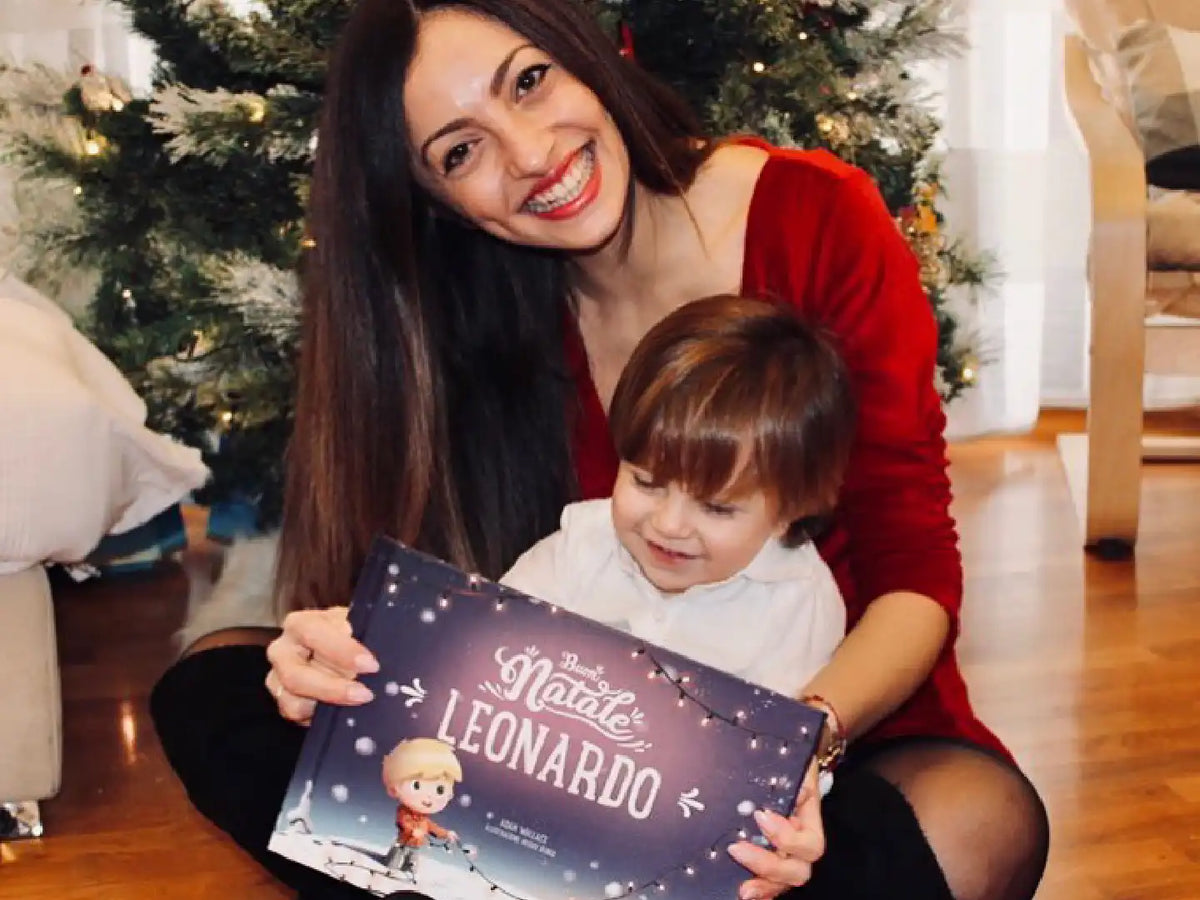 Una madre seduta con il suo bambino davanti all'albero di Natale che sorride e mostra il regalo più carino di Urrà Eroi. 