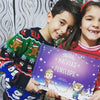 Due bambini sorridono alla macchina fotografica con il loro libro personalizzato da Urrà Eroi 