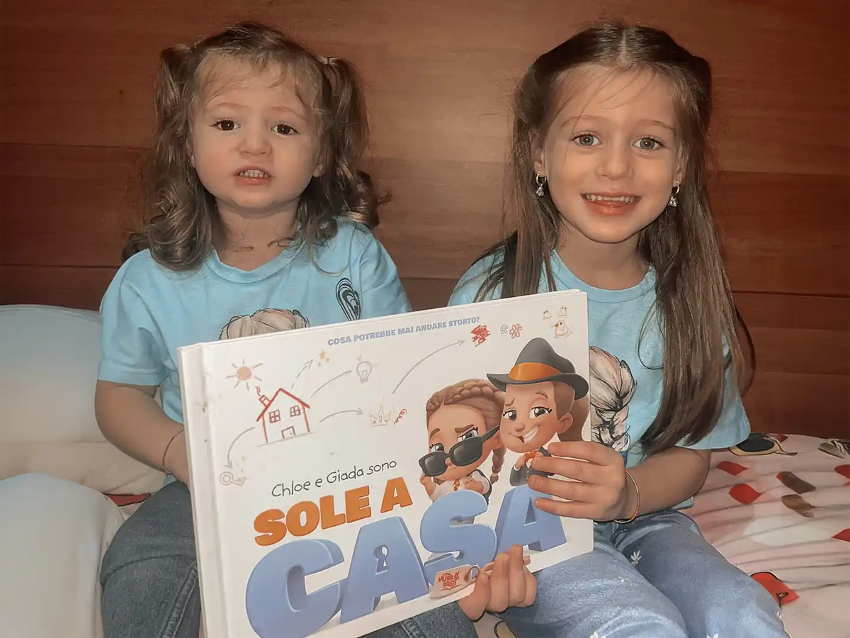 Due sorelle con in mano un libro personalizzato sullo stare a casa da sole.