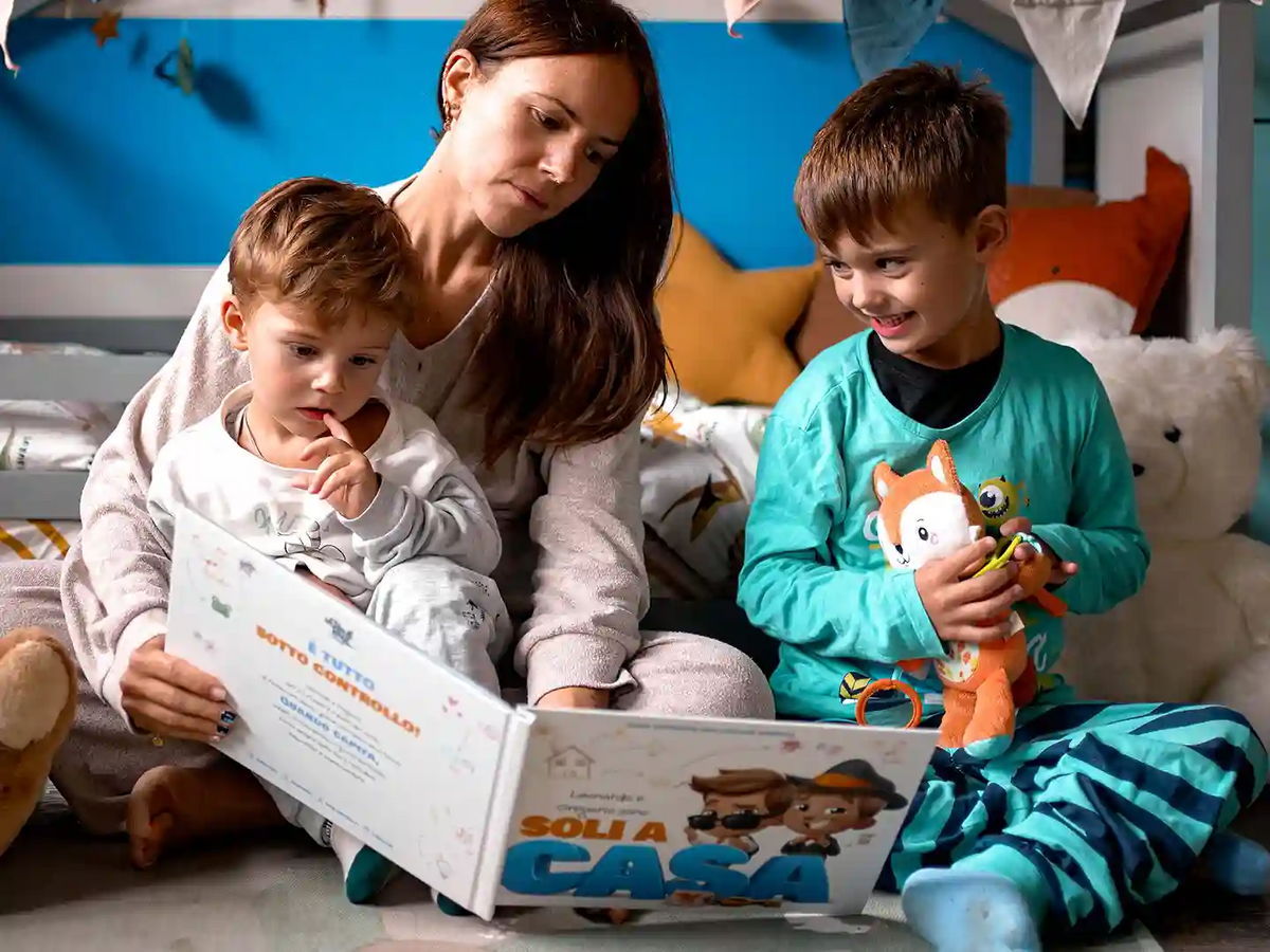 Una mamma sta leggendo ai suoi figli un libro personalizzato per i fratelli.