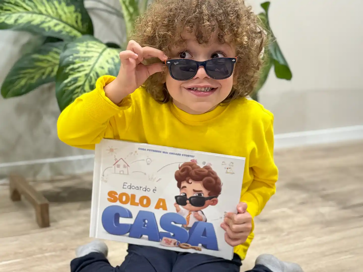 Un ragazzino con in mano il suo libro personalizzato sullo stare a casa da solo.