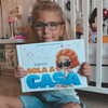Una bambina con il suo nuovo libro personalizzato sull'essere a casa da soli di Urrà Eroi.
