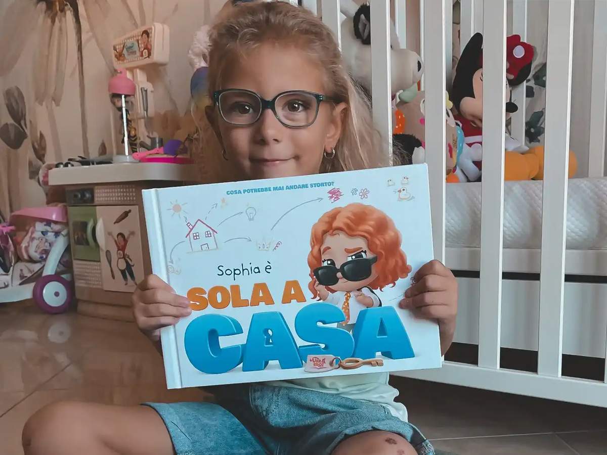 Una bambina con il suo nuovo libro personalizzato sull'essere a casa da soli di Urrà Eroi.