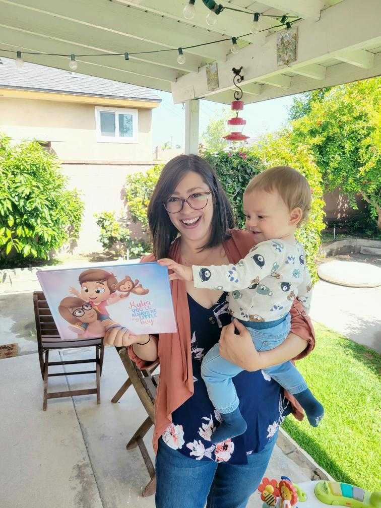 Una madre tiene in braccio il suo bambino e il suo libro personalizzato e sorride