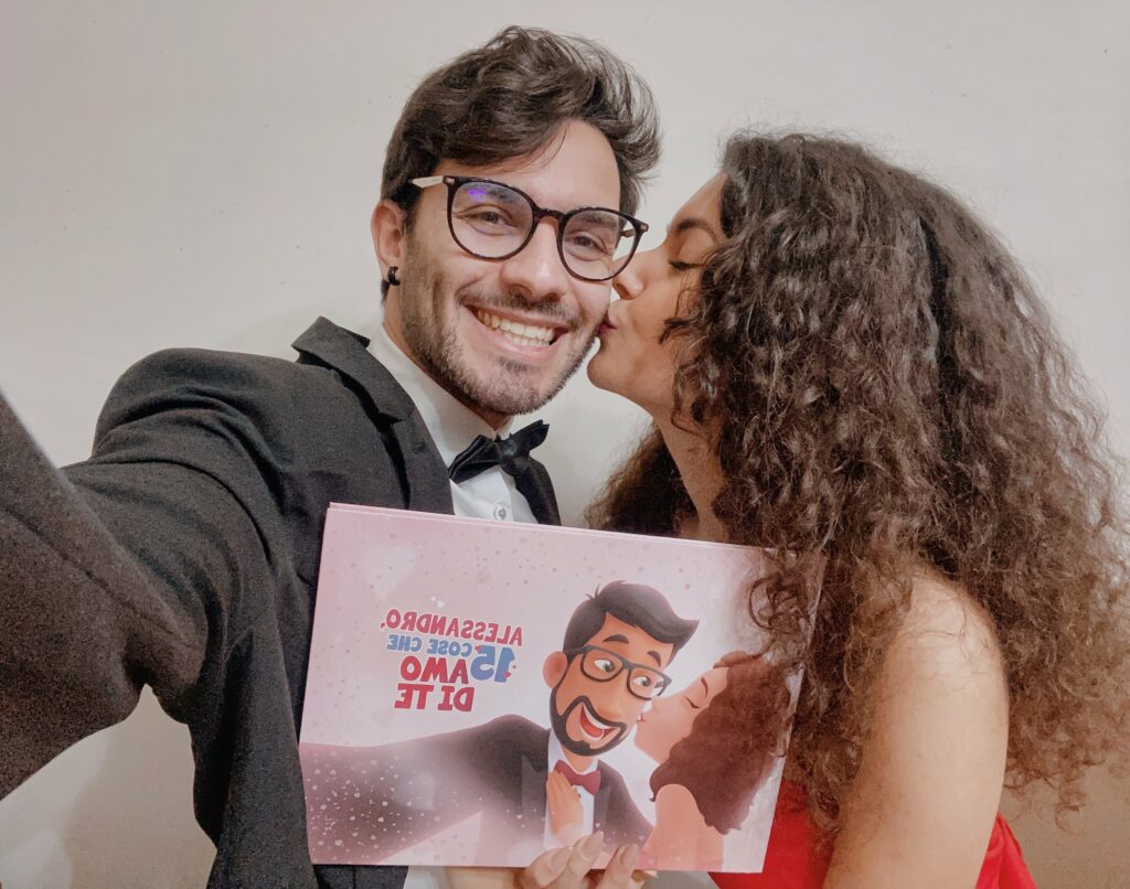 La foto mostra una coppia felice che si bacia e presenta il proprio libro d'amore personalizzato.