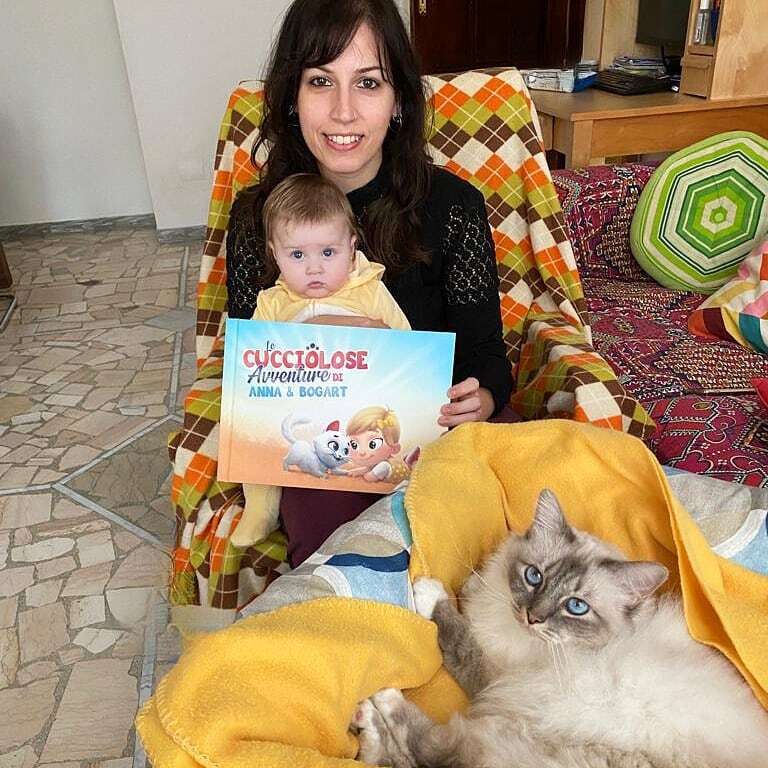 Una mamma con in braccio il suo bambino e il libro personalizzato per bambini e gatti. 