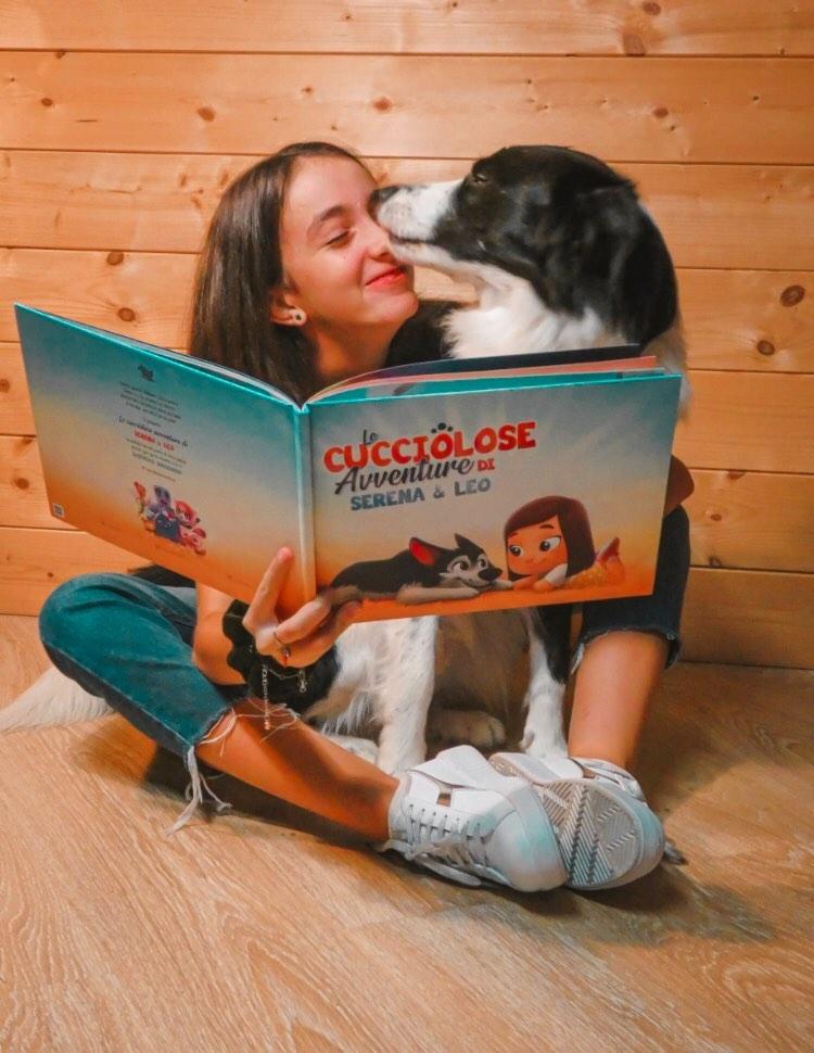 Un cane che lecca il viso di una ragazza mentre legge il libro personalizzato per animali domestici.