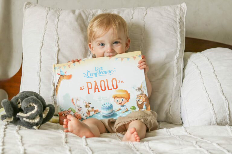 Un bambino seduto sul divano con un libro personalizzato e un peluche.