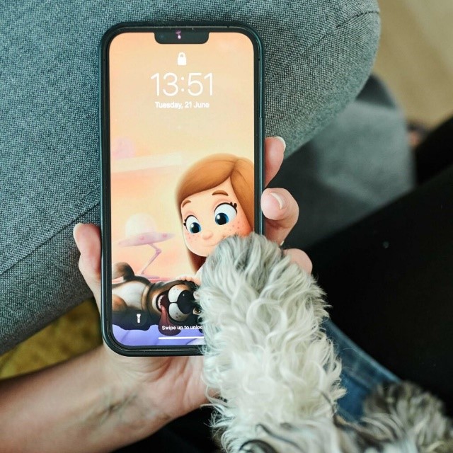Un cane ha messo la zampa su un telefono cellulare con uno sfondo personalizzato.
