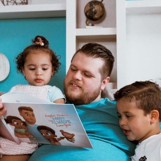 Un padre legge il libro personalizzato Papà vi amerà per sempre con i suoi due figli seduti sul divano.