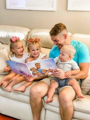 Un padre legge il libro personalizzato Papà vi amerà per sempre con i suoi tre figli seduti sul divano.
