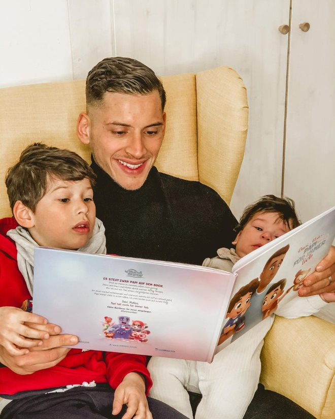 Un padre legge il libro personalizzato di Urrà Eroi con i suoi due figli in poltrona.