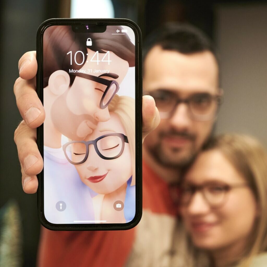 Una coppia tiene in mano un cellulare che mostra lo sfondo personalizzato.
