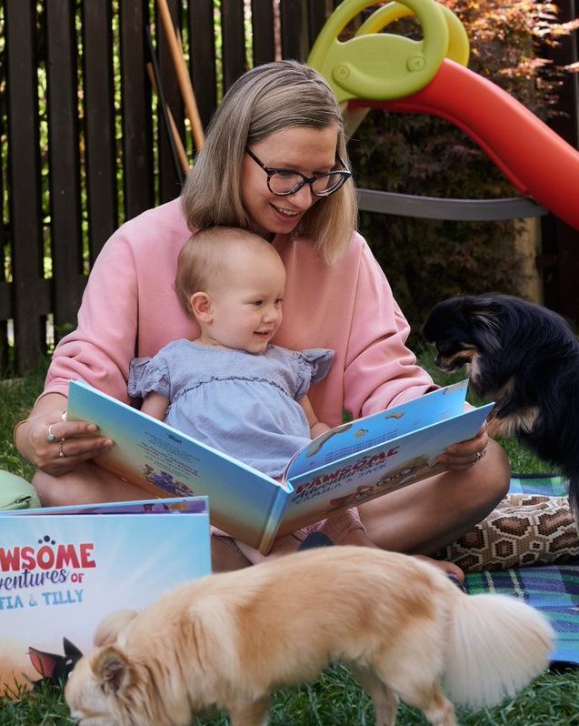 Una madre legge il libro personalizzato di Urrà Eroi alla figlia e al cane.
