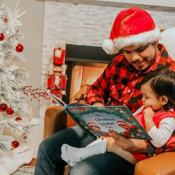 Un padre e un figlio seduti in poltrona che leggono il loro libro di Natale personalizzato