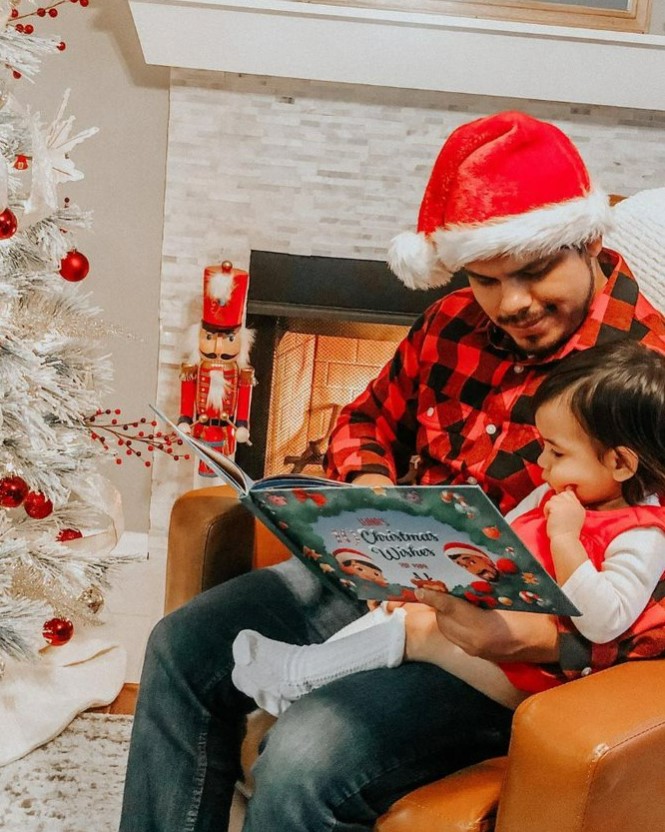 Un padre e un figlio seduti in poltrona che leggono il loro libro di Natale personalizzato