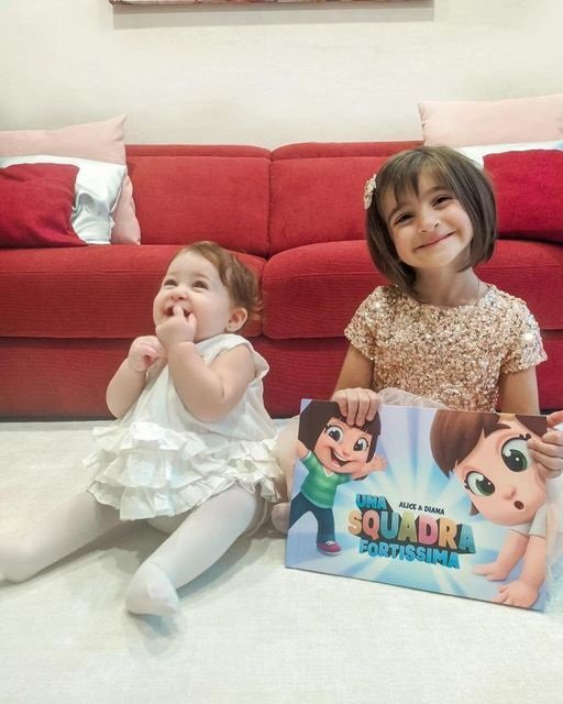 Due bambine mostrano il loro libro personalizzato per i fratelli.