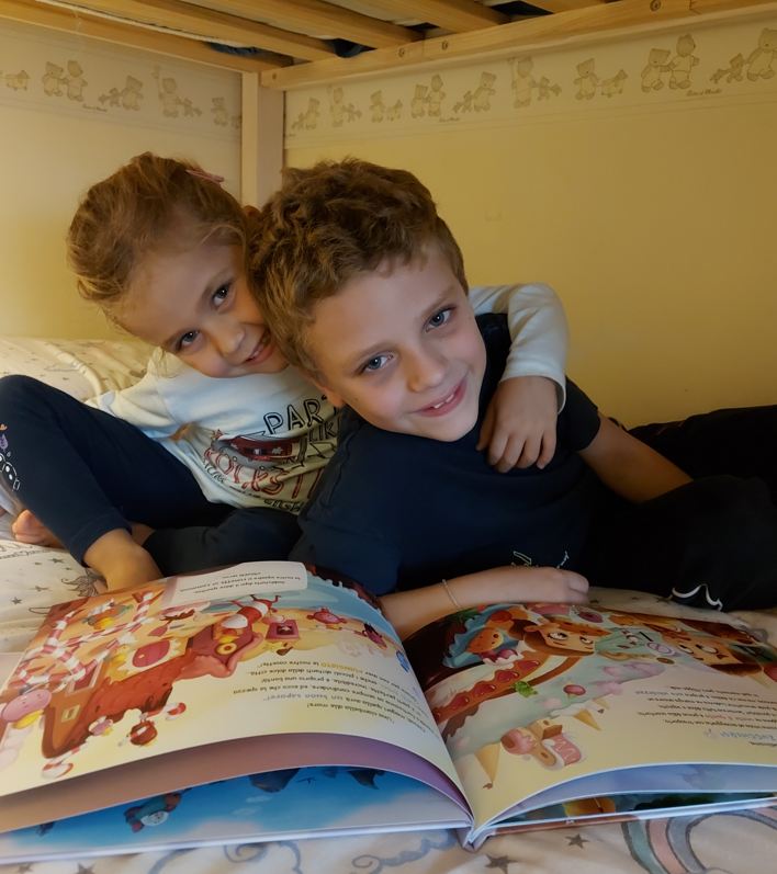 Due fratelli e sorelle leggono il loro libro personalizzato per fratelli e sorelle nel letto.