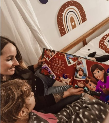 Madre e figlia leggono un libro personalizzato per Natale di Urrà Eroi.