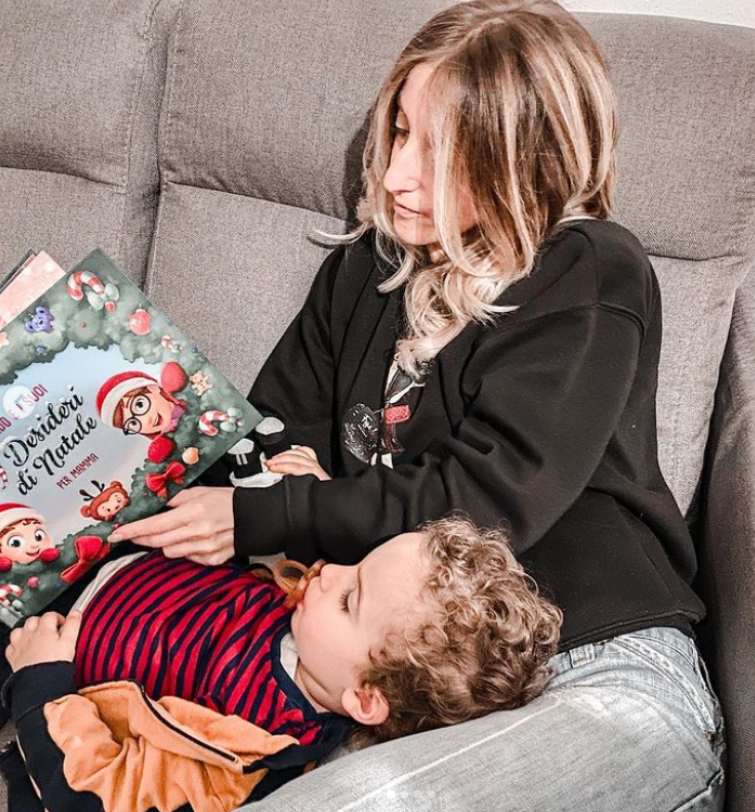 Una madre e un figlio sul divano che leggono il libro personalizzato di Urrà Eroi 10 desideri per Natale