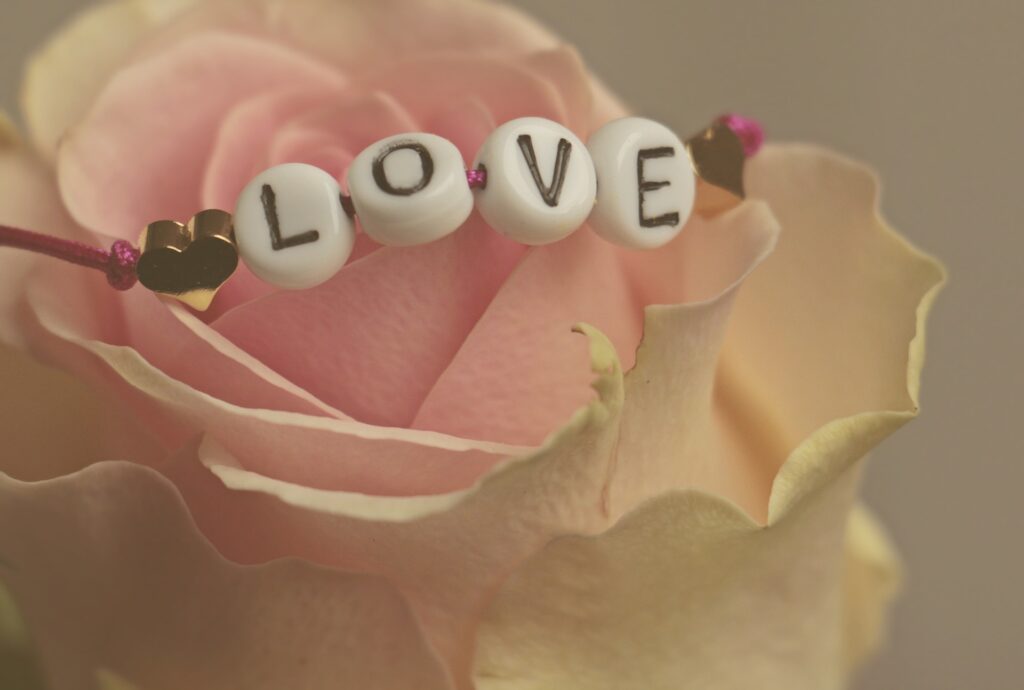 L'immagine mostra una rosa e un braccialetto con la scritta amore.